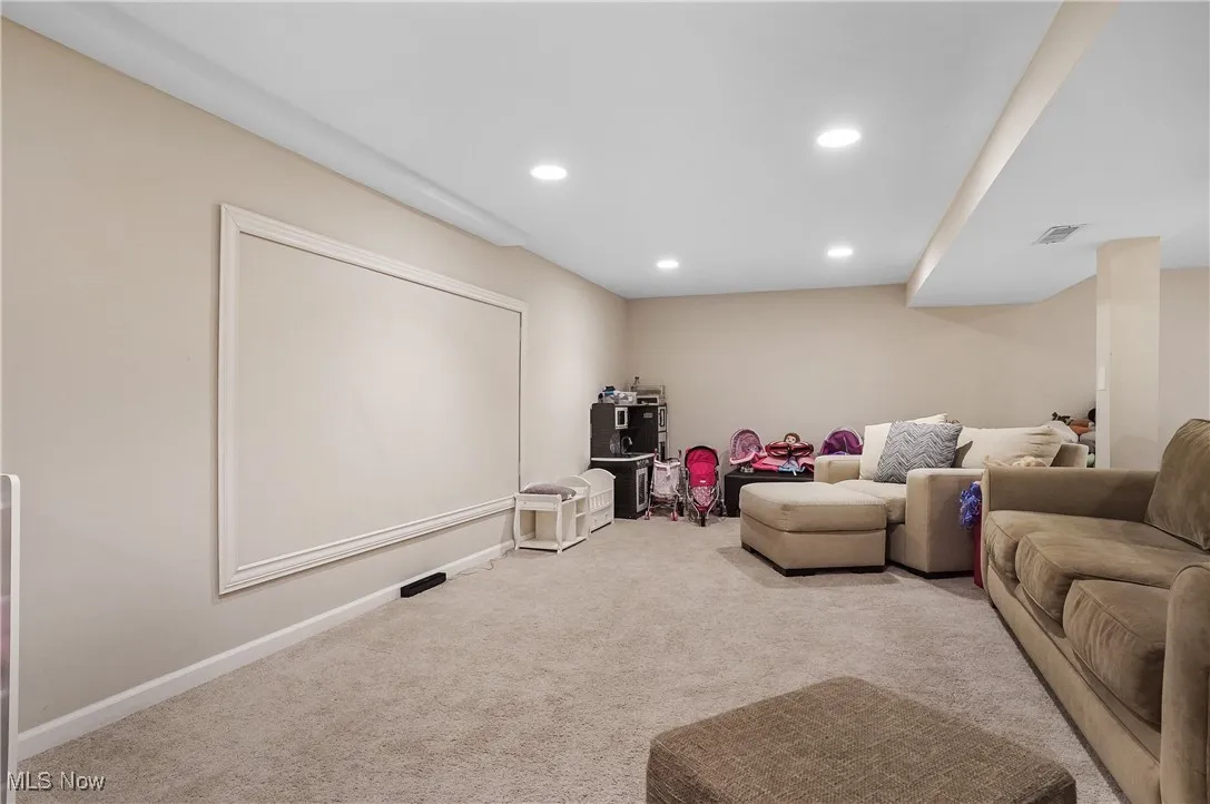 Carpeted living area with recessed lighting and baseboards
