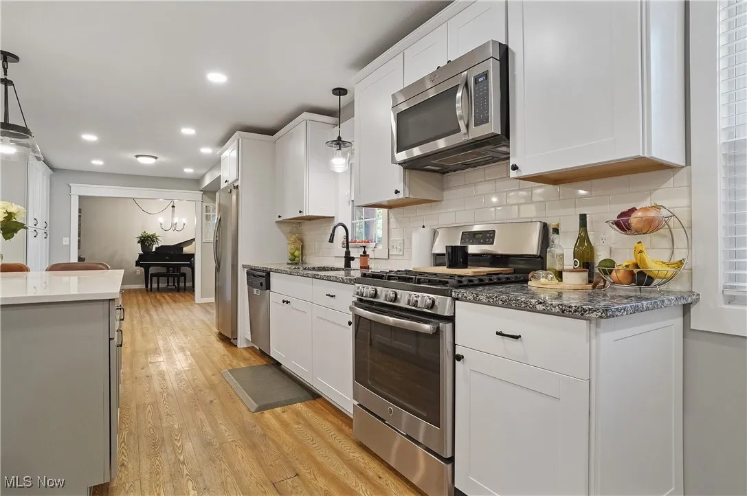 Kitchen featuring stainless steel appliances, white cabinetry, pendant lighting, light wood lvt flooring, and recessed lighting