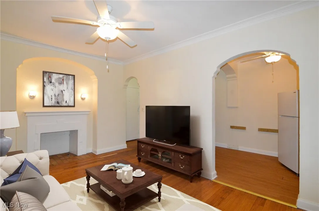 Virtually Staged Living room with a ceiling fan, crown molding, wood finished floors, and a fireplace
