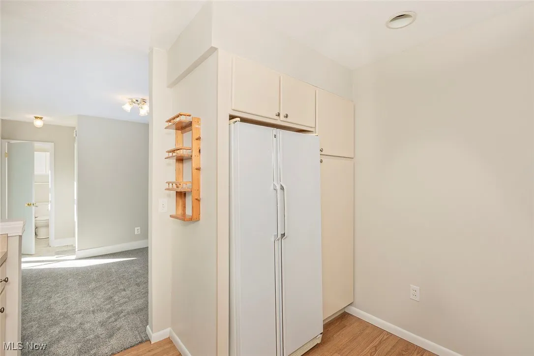 Kitchen featuring freestanding refrigerator, light wood finished floors, and cream cabinets