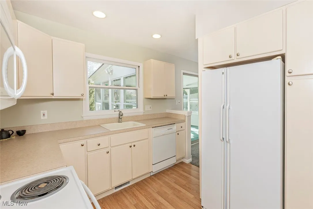 Kitchen with white appliances, light countertops, light wood-type flooring, and recessed lighting