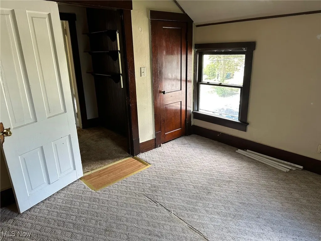 Unfurnished bedroom featuring light carpet and lofted ceiling