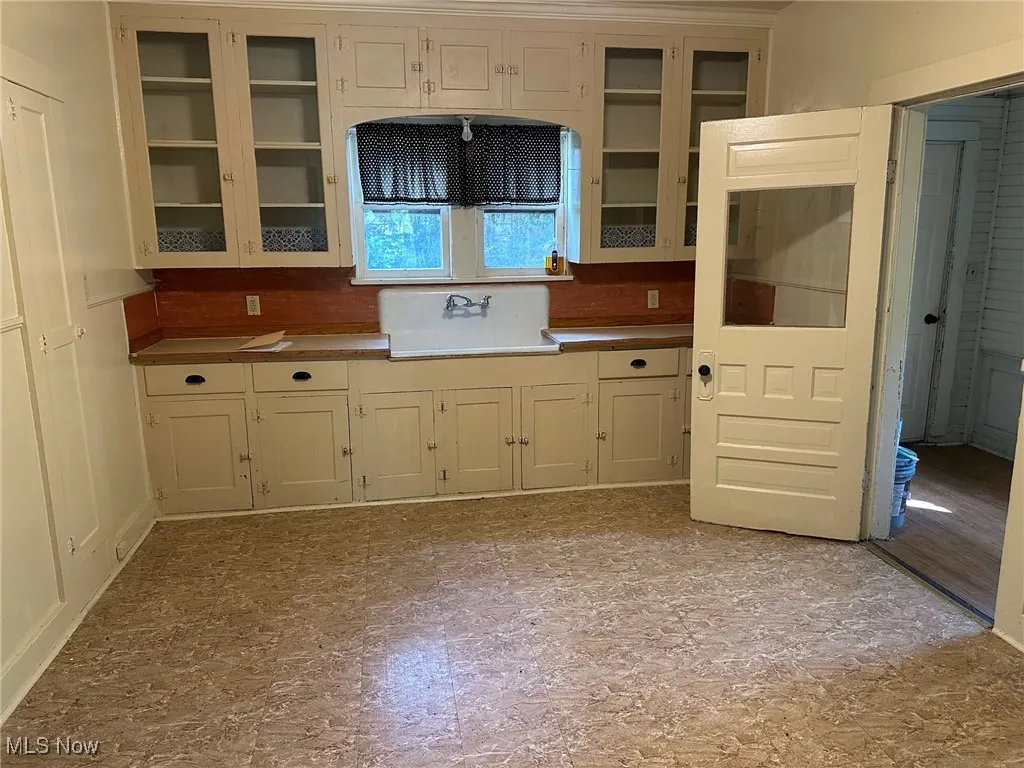 Kitchen featuring light countertops, glass insert cabinets, and cream cabinets