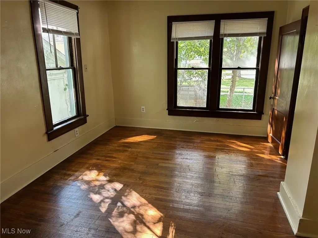 Unfurnished room with dark wood-style floors and baseboards