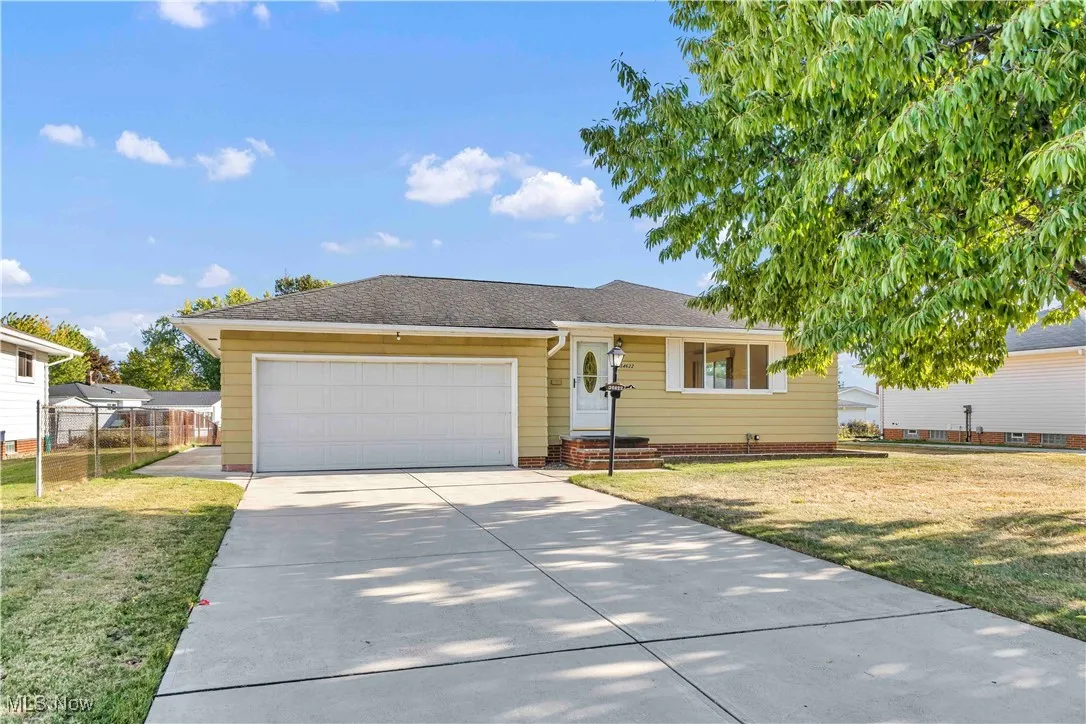Ranch with a newer paved driveway, two car attached garage, and a shingled roof