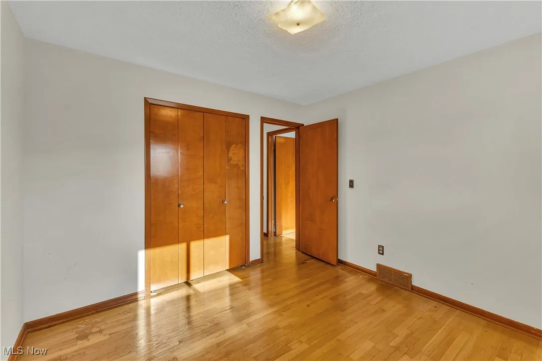 Third bedroom with hardwood floors and a double-door closet