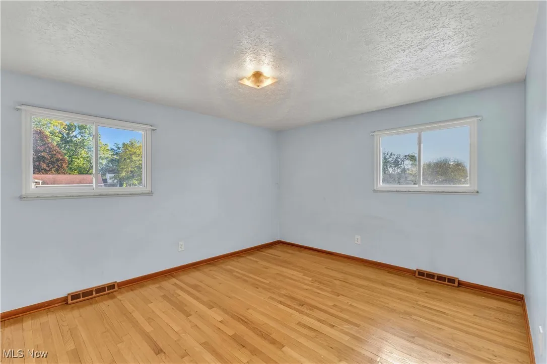 Primary bedroom features hardwood floors and would comfortably fit a queen or king-sized bed