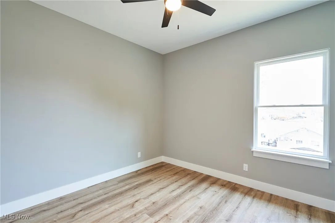 Spare room with ceiling fan, a healthy amount of sunlight, and light wood-type flooring