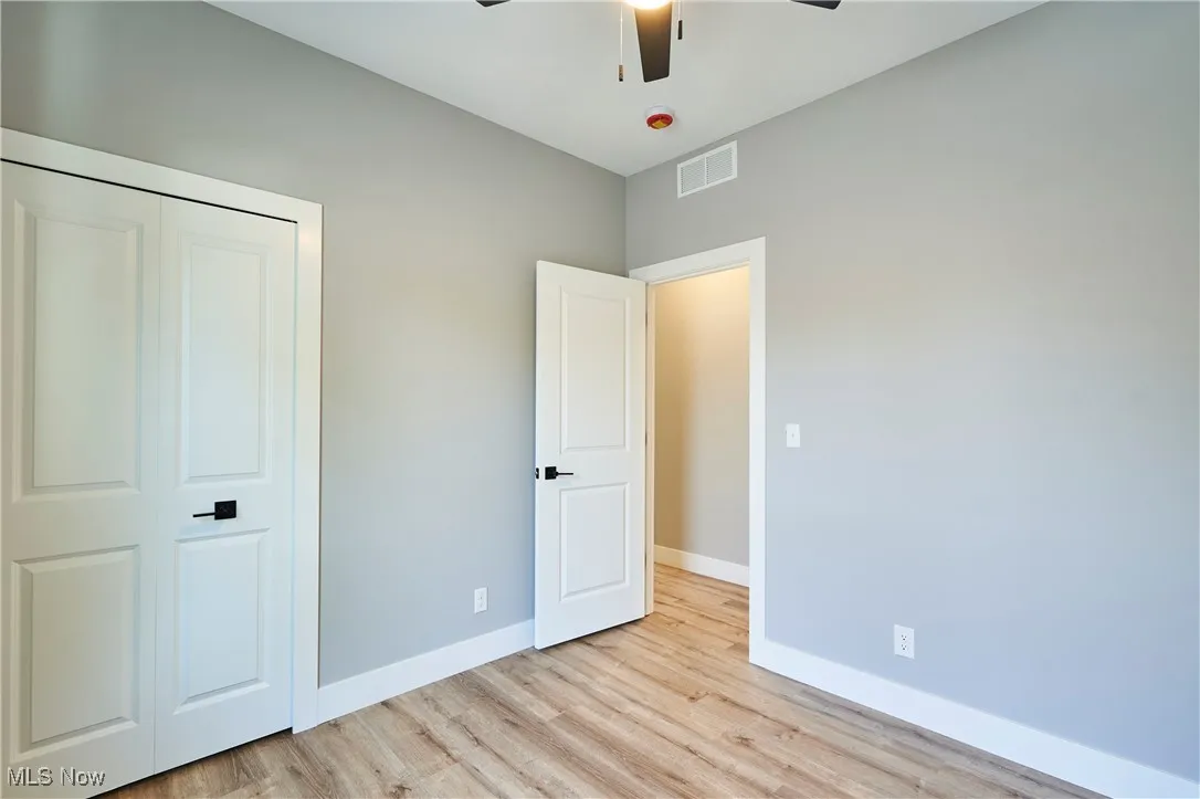 Unfurnished bedroom featuring light hardwood / wood-style flooring, a closet, and ceiling fan