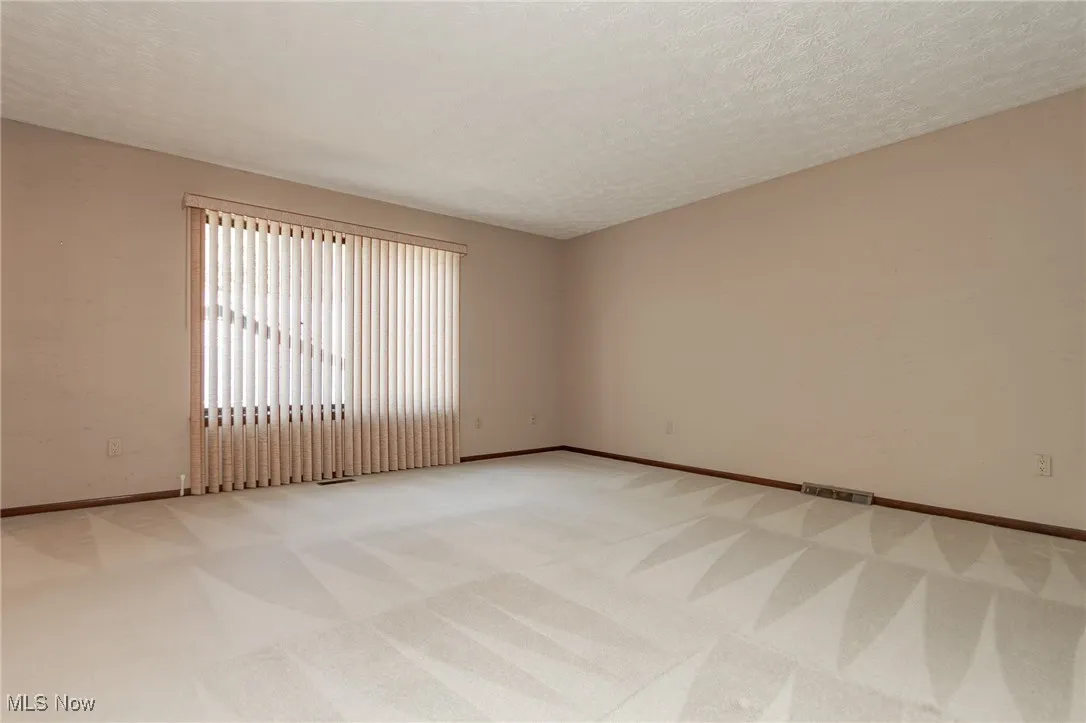 Empty room with a textured ceiling and light carpet