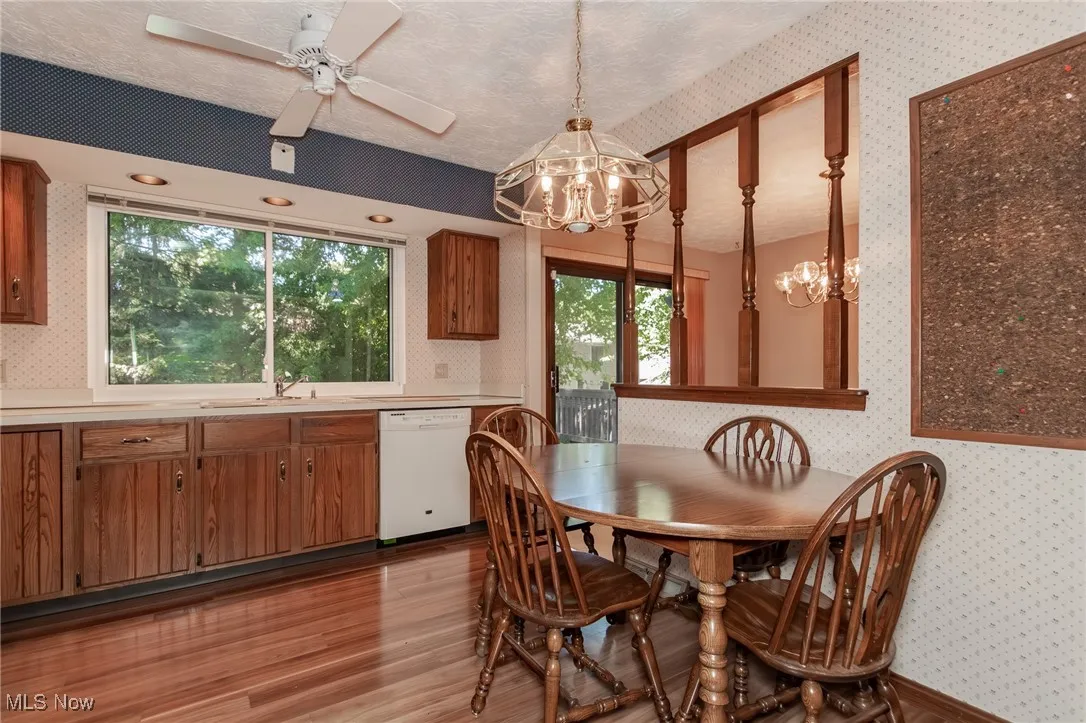 Dining space with wallpapered walls, a chandelier, a textured ceiling, light wood-style flooring, and ceiling fan