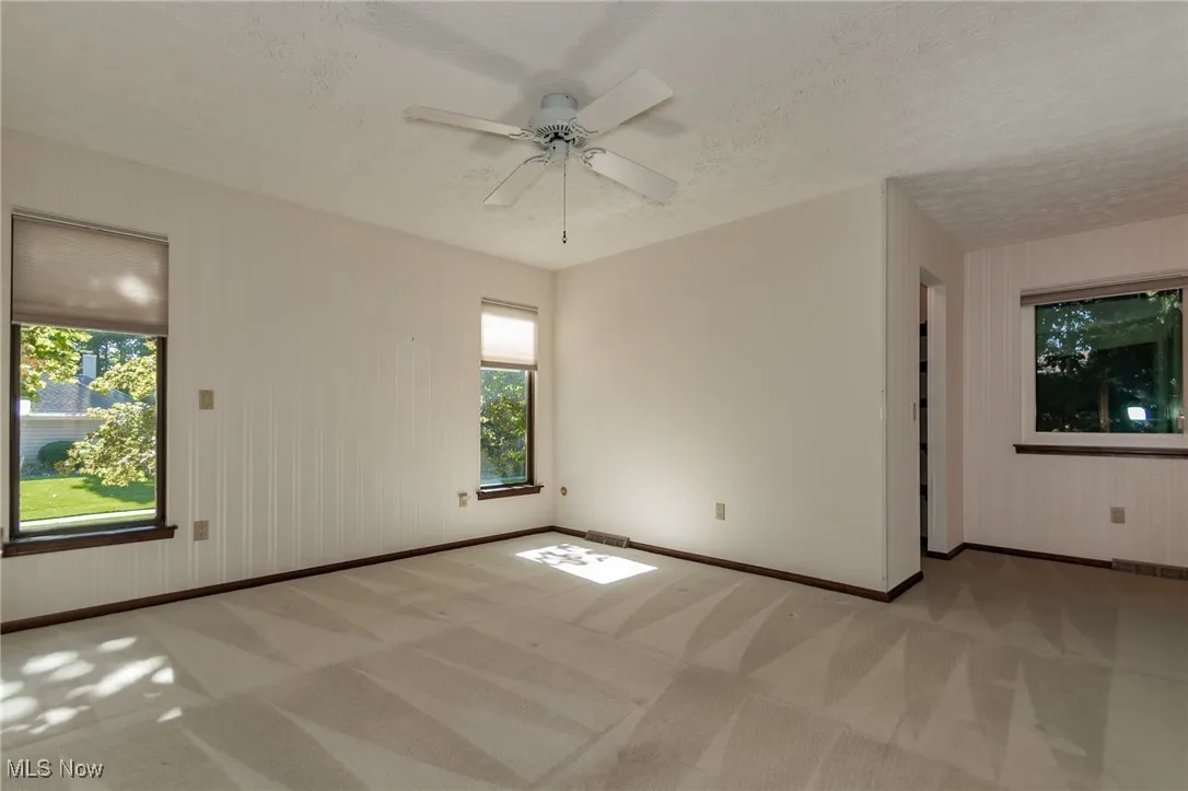 Carpeted spare room featuring a textured ceiling, wooden walls, and ceiling fan