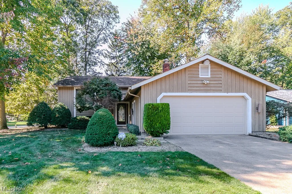 View of front of house with a garage, concrete driveway, a front lawn, a chimney, and roof with shingles