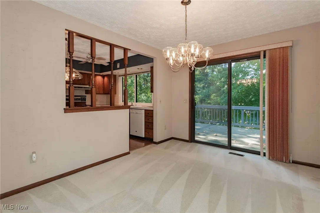 Unfurnished dining area featuring light colored carpet, a textured ceiling, and a chandelier