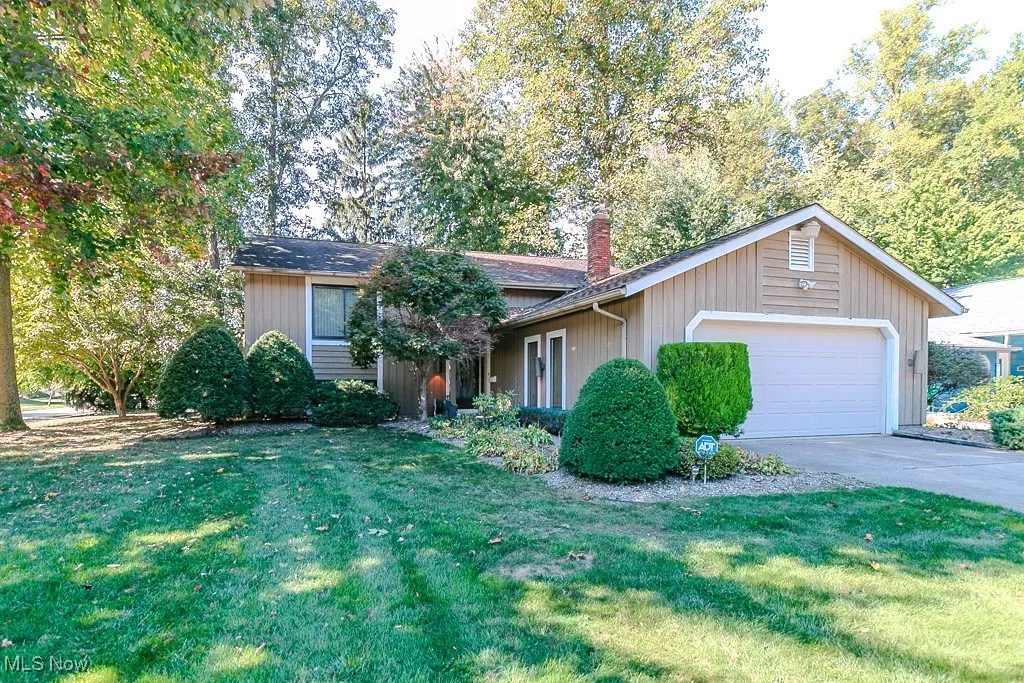 View of front of house featuring a front lawn, a garage, concrete driveway, and a chimney