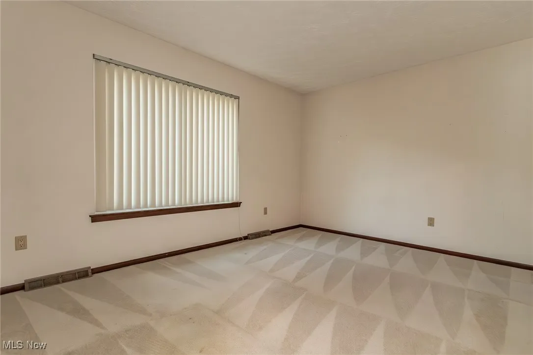 Empty room with light colored carpet and baseboards
