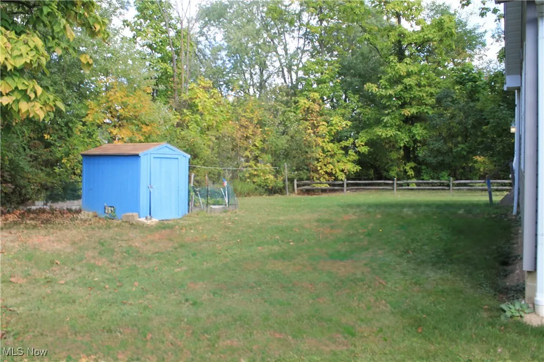 Fenced backyard featuring a storage shed and view of scattered trees