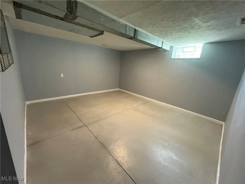 Basement featuring baseboards and a textured ceiling