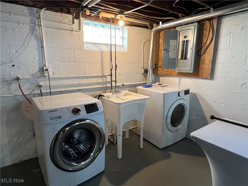 Washroom featuring electric panel and washing machine and clothes dryer