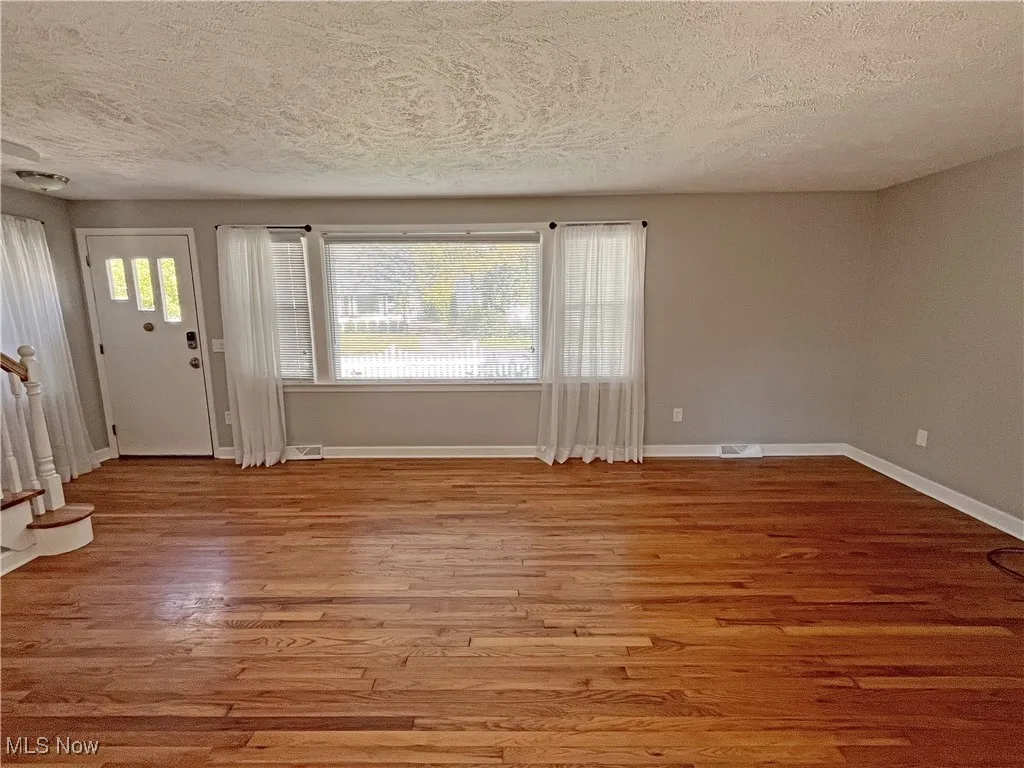 Entryway featuring a textured ceiling, plenty of natural light, light wood finished floors, and stairs