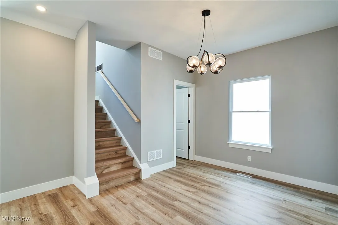 Spare room featuring an inviting chandelier and light hardwood / wood-style floors