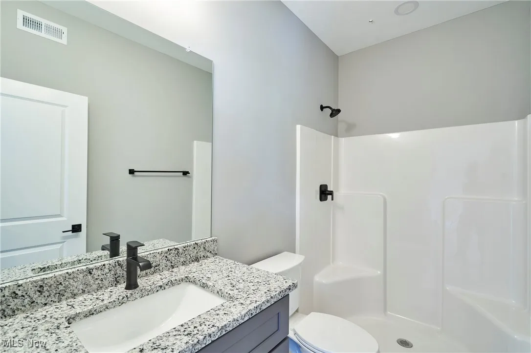 Bathroom featuring vanity, toilet, and walk in shower