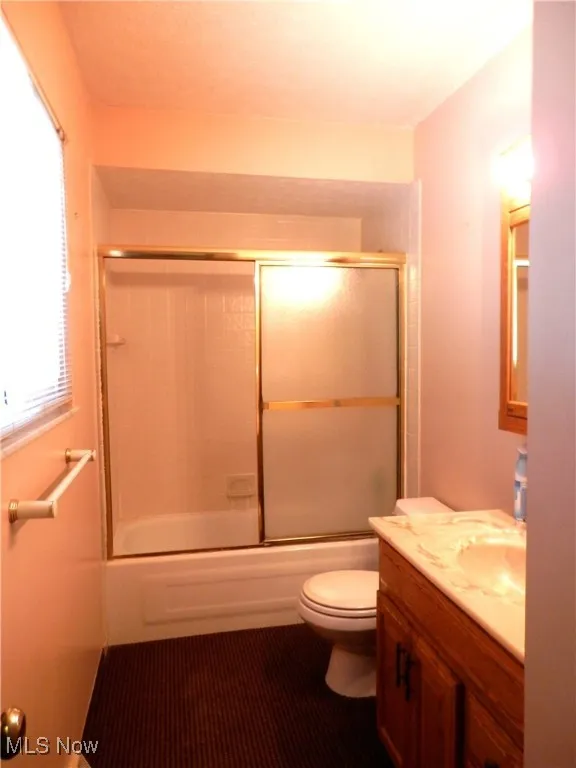 Full bath featuring shower / bath combination with glass door and vanity