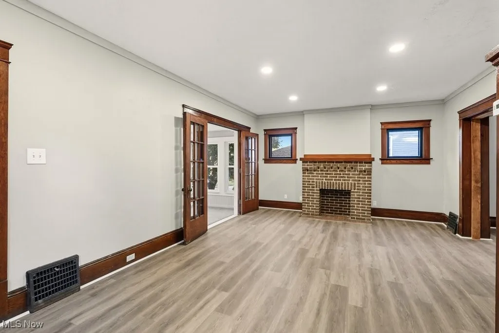 Unfurnished living room with healthy amount of natural light, light wood-style flooring, recessed lighting, a fireplace, and crown molding