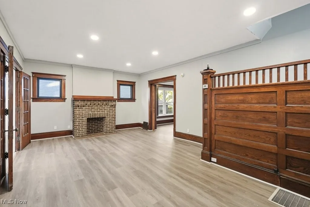 Unfurnished living room with recessed lighting, light wood-style floors, a brick fireplace, and ornamental molding