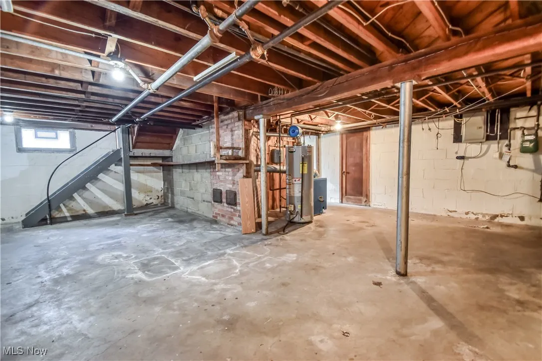 Below grade area with stairway, gas water heater, and electric panel