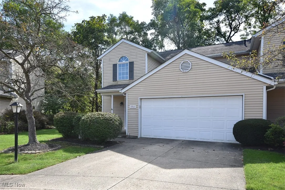 Traditional-style home featuring driveway, a front lawn, and an attached garage
