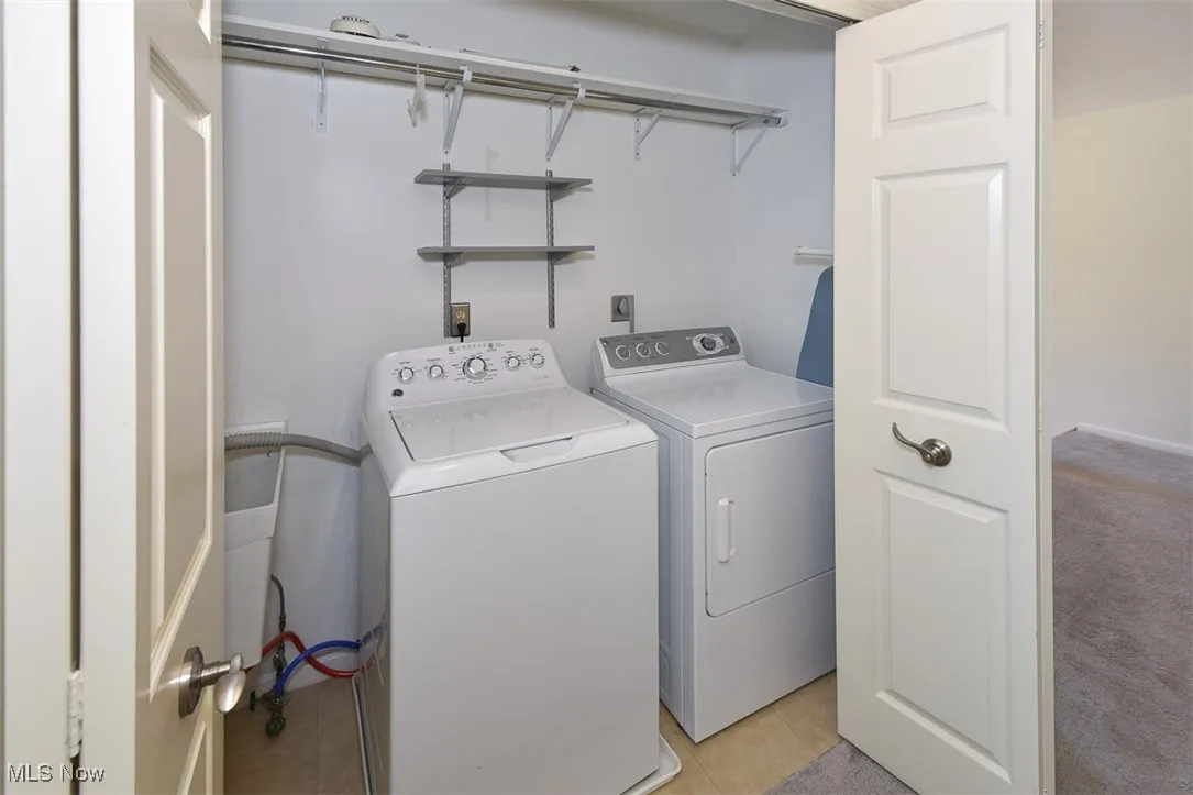 Laundry area with washer and dryer and light tile patterned flooring