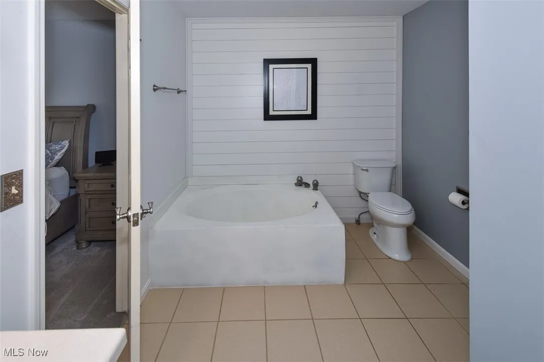 Full bathroom featuring a garden tub, light tile patterned flooring, and wooden walls