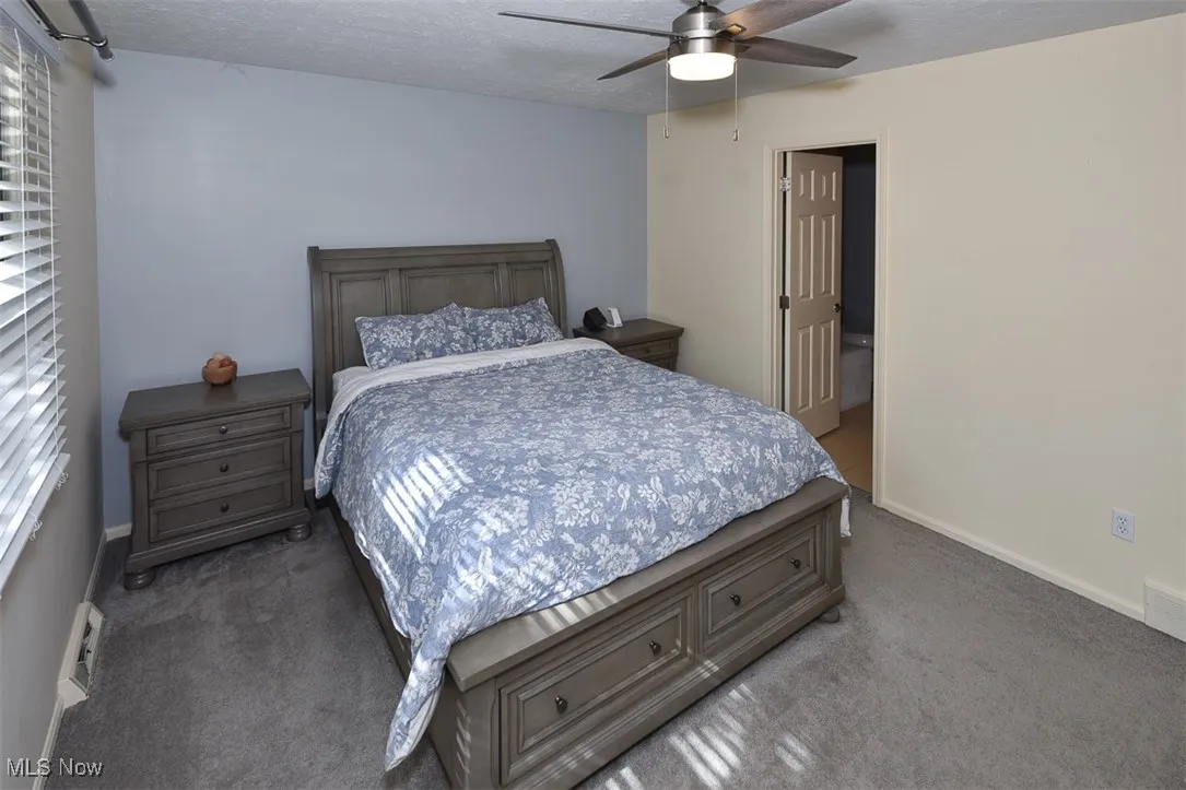 Carpeted bedroom featuring a textured ceiling and a ceiling fan