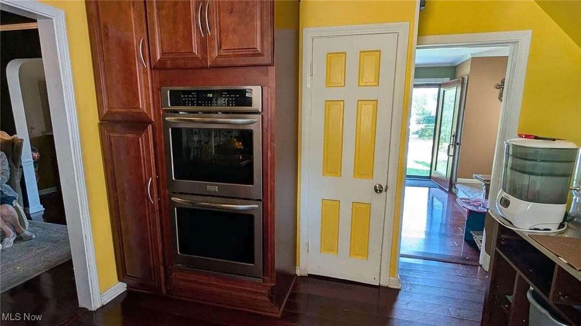 Kitchen featuring stainless steel double oven and dark wood-style floors