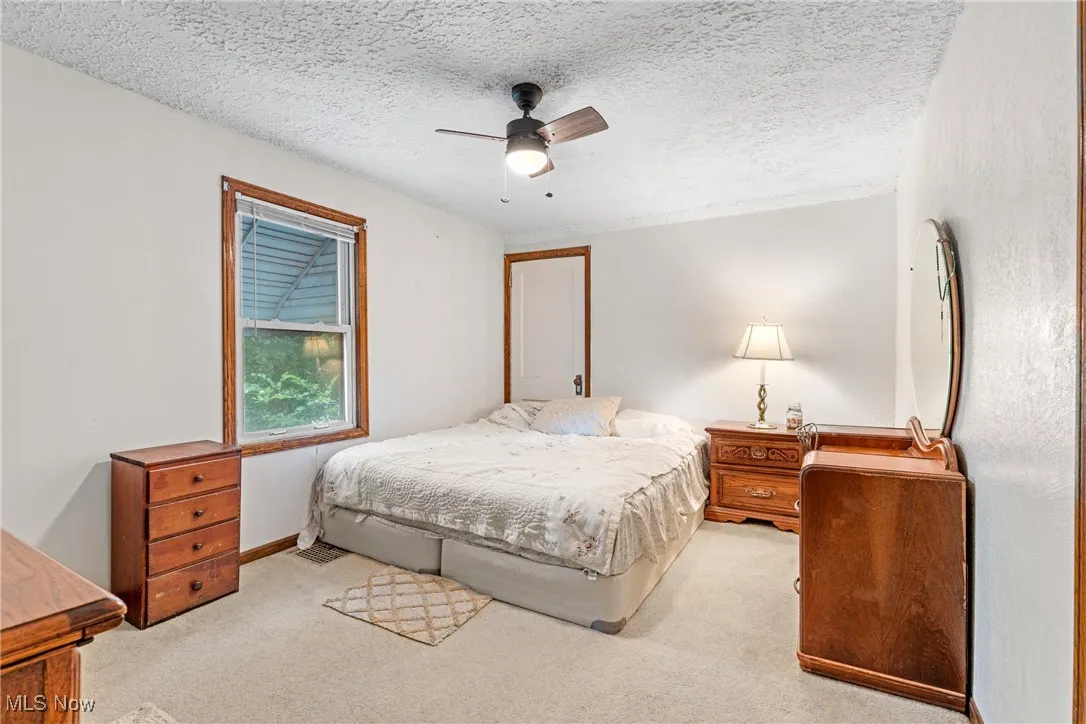 Carpeted bedroom with a textured ceiling and a ceiling fan