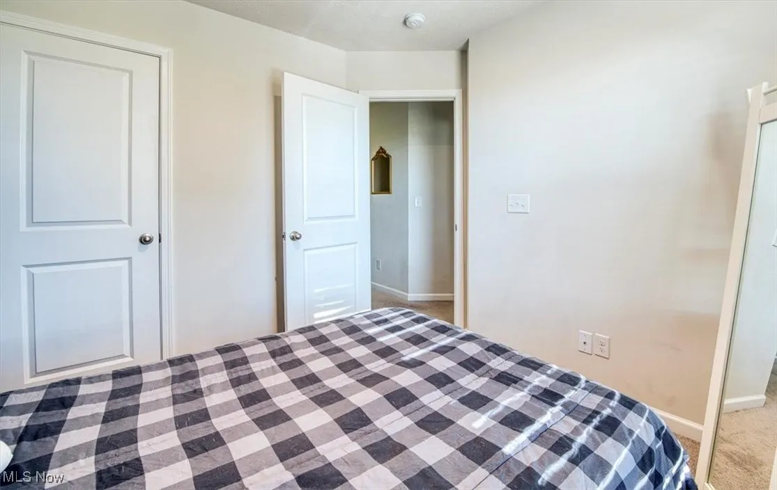 Bedroom with baseboards and light colored carpet