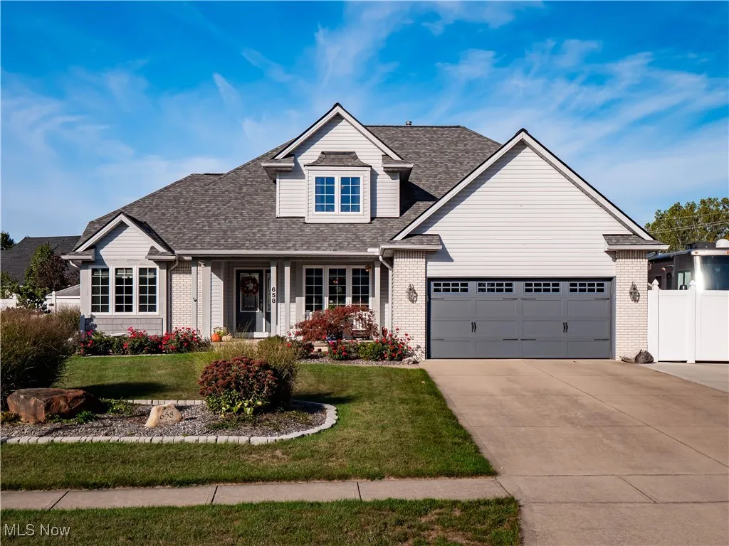 View of front of property featuring brick siding, a shingled roof, driveway, and covered porch