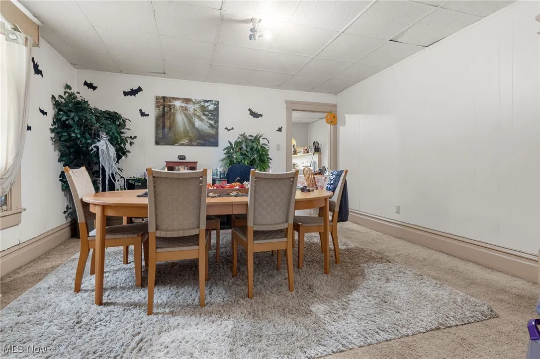 Dining room with light colored carpet and a drop ceiling