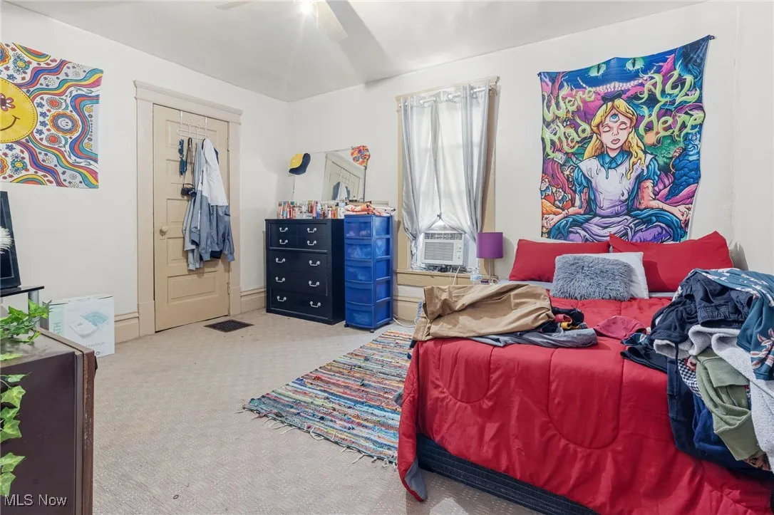 Carpeted bedroom with a closet, ceiling fan, and cooling unit