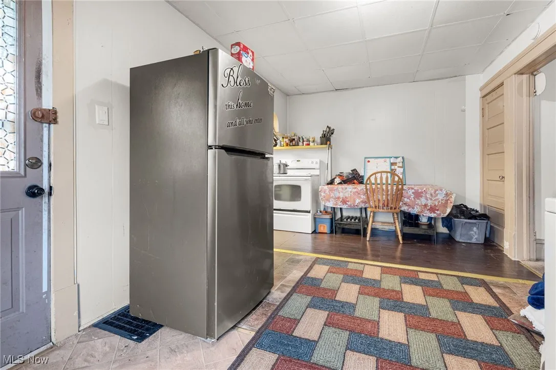 Kitchen featuring freestanding refrigerator, a drop ceiling, and white range with electric cooktop