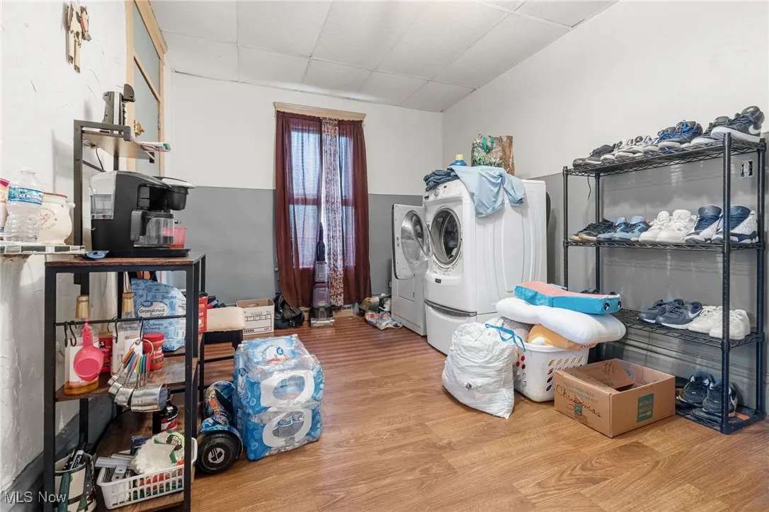 Washroom featuring a drop ceiling, washer and clothes dryer, and light wood-type flooring