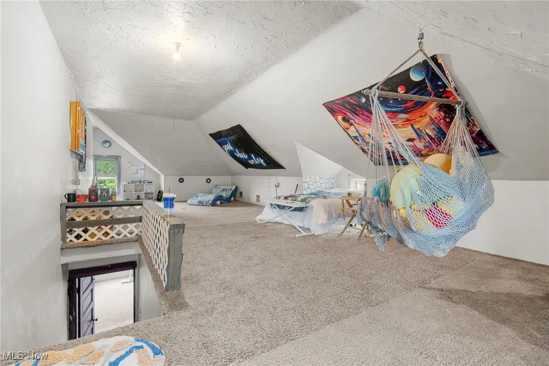Rec room with a textured ceiling, carpet floors, and vaulted ceiling