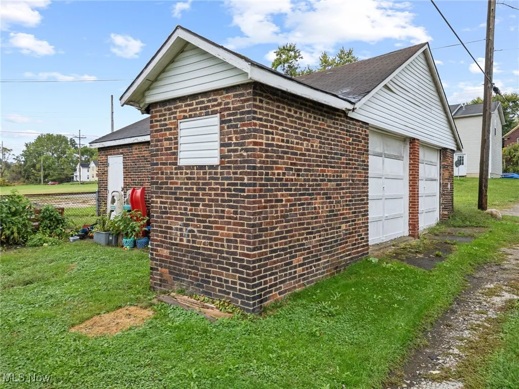 View of home's exterior featuring a garage, brick siding, and a yard