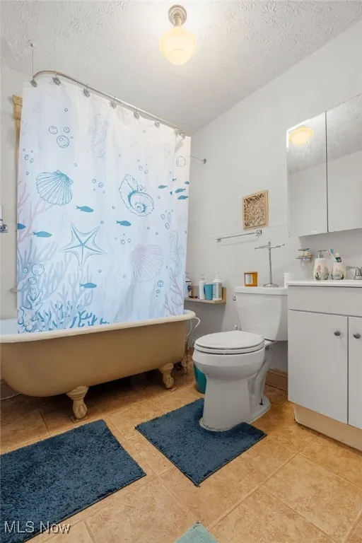 Bathroom with a textured ceiling, vanity, a combined bath / shower with freestanding tub, and light tile patterned floors