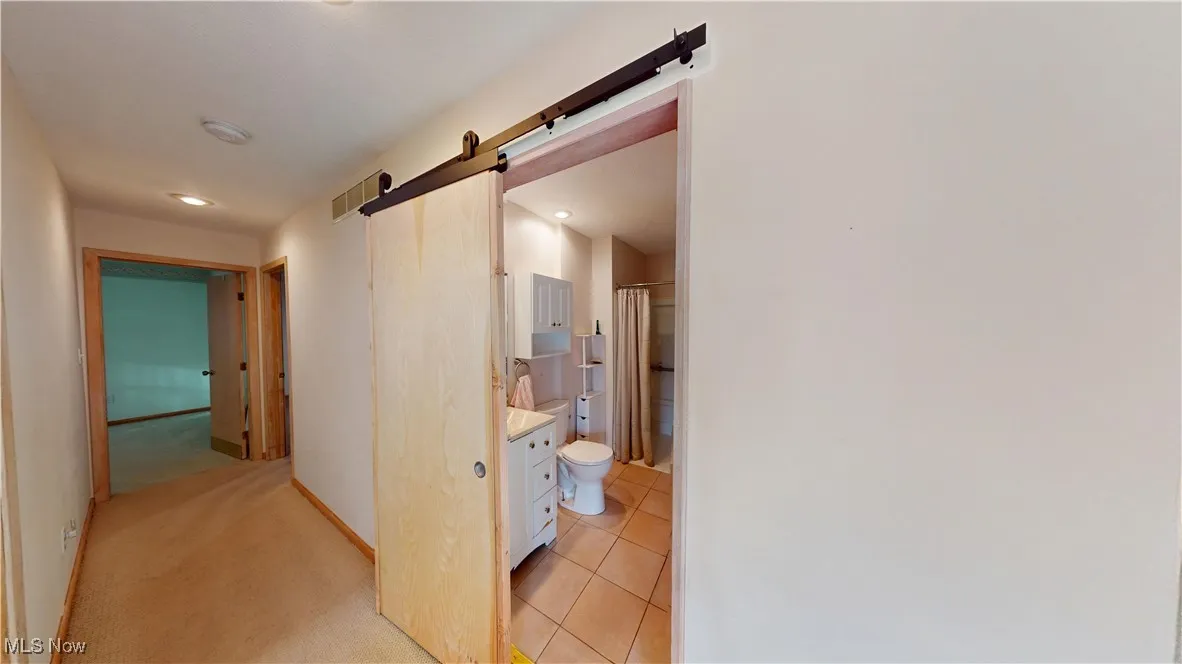 Hallway showing entry to hall bathroom which features a sliding door.