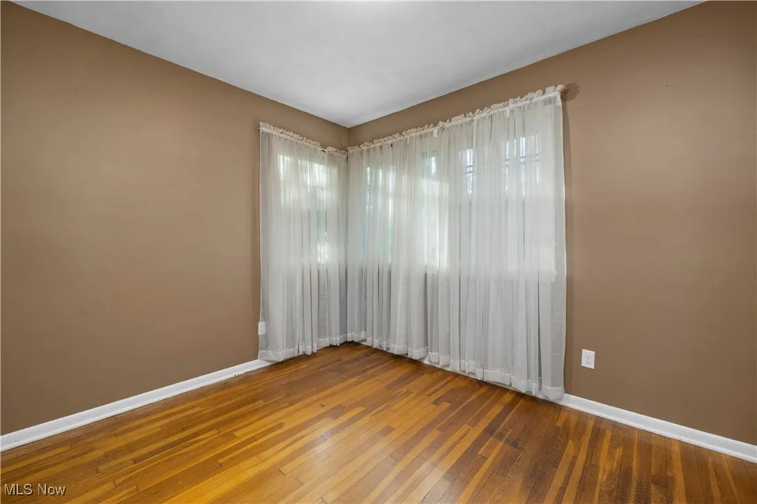 Unfurnished room with baseboards and wood-type flooring