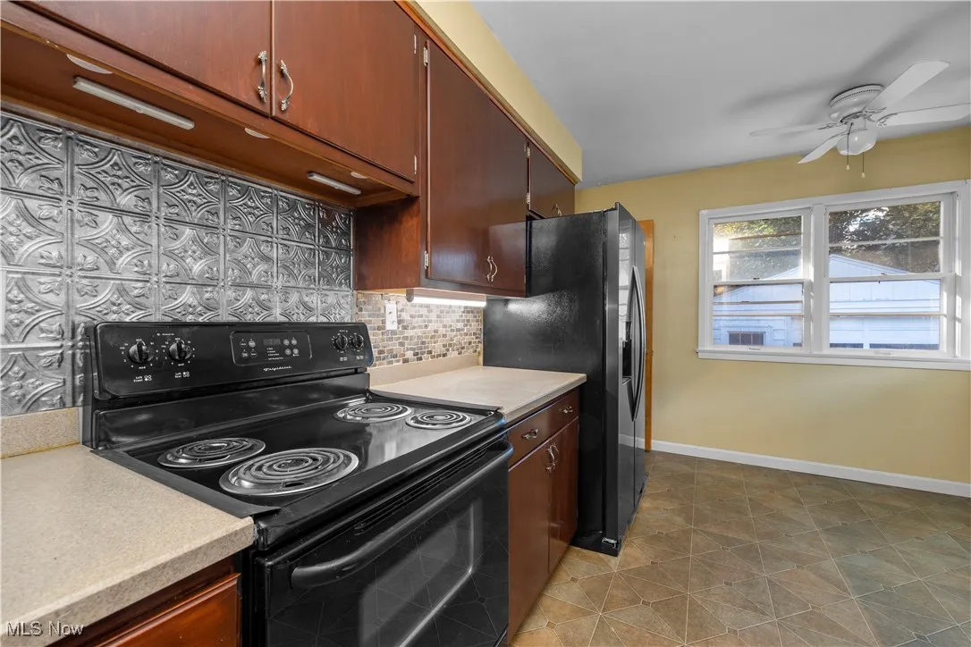 Kitchen with black appliances, tasteful backsplash, light countertops, and ceiling fan