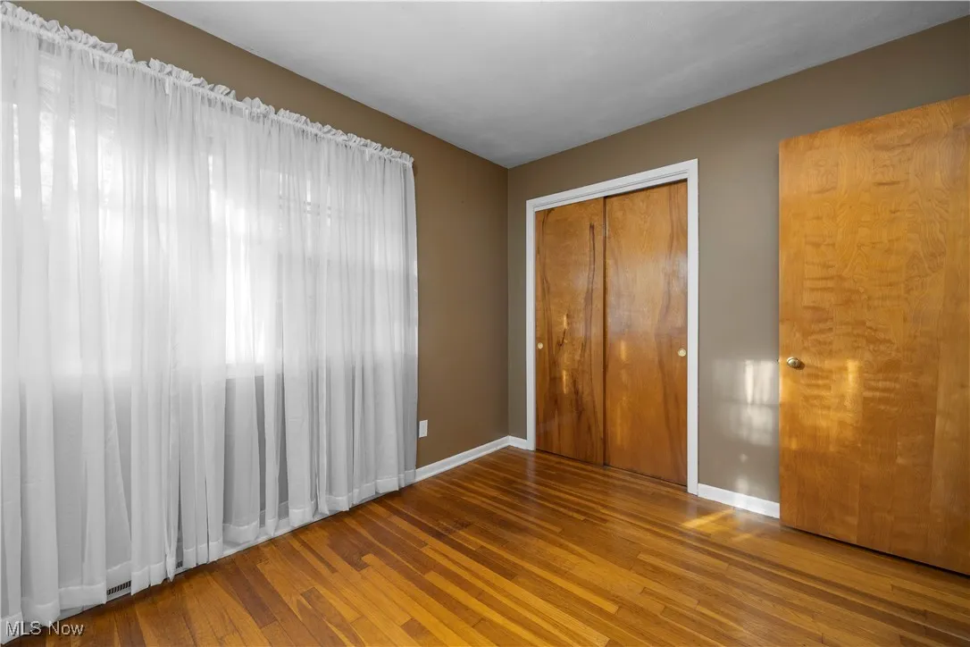 Unfurnished bedroom with dark wood-style floors and a closet