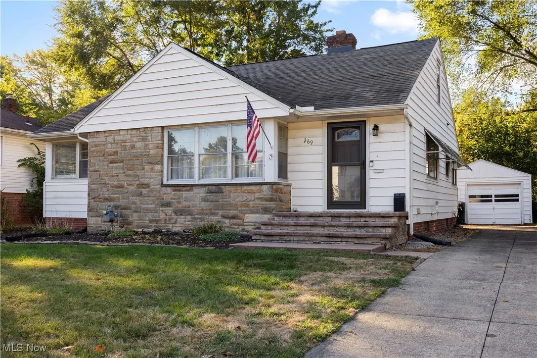 View of front of house featuring an outdoor structure, a chimney, a front lawn, and a shingled roof
